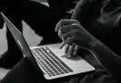grayscale photo of person using MacBook